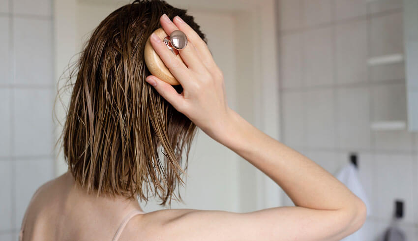 A woman massaging her head with scalp massager